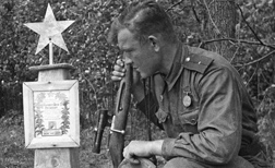 Снайпер 61 армии младший лейтенант Иван Лебедев / на его счету 203 убитых немца / у могилы боевого товарища. Брянский фронт. 1943 год.